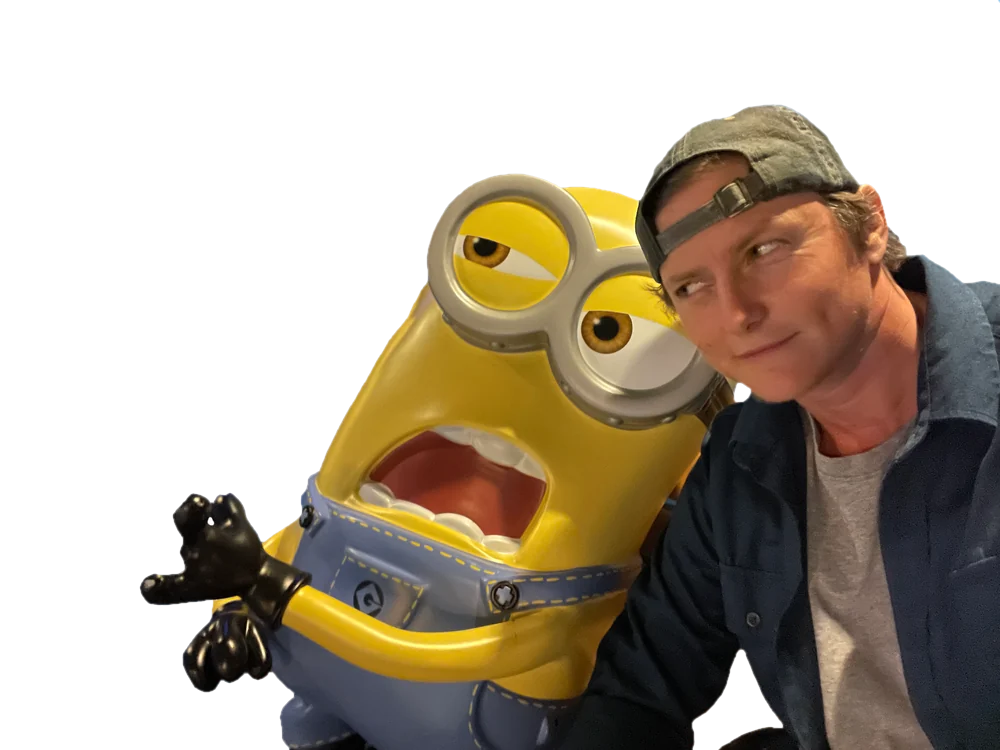 Phoenix in a backwards cap, leaning on a big Minion figure.